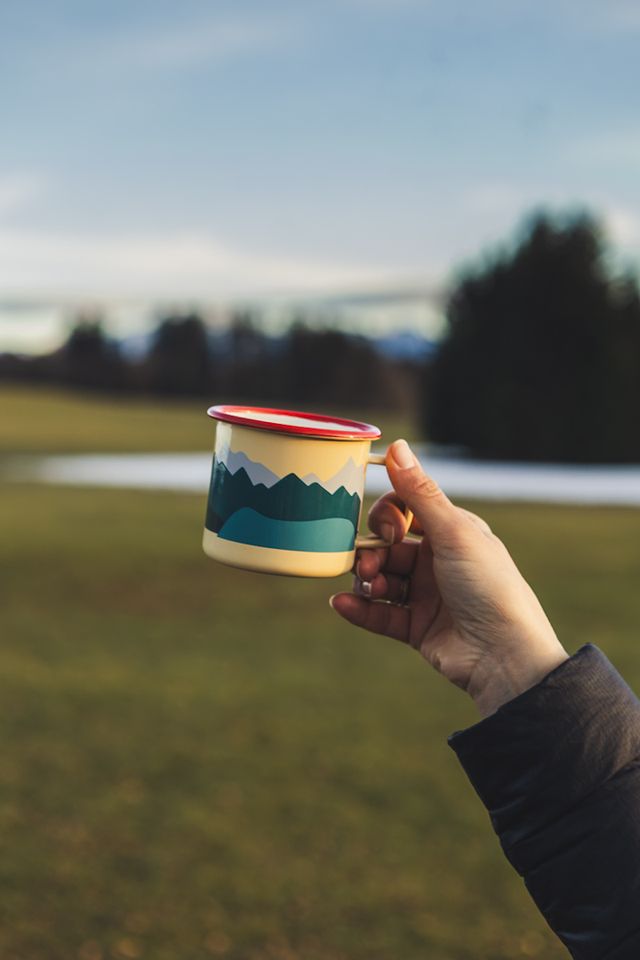 gelbe Emaille Tasse mit rotem Rand und einem Aufdruck von Bergen
