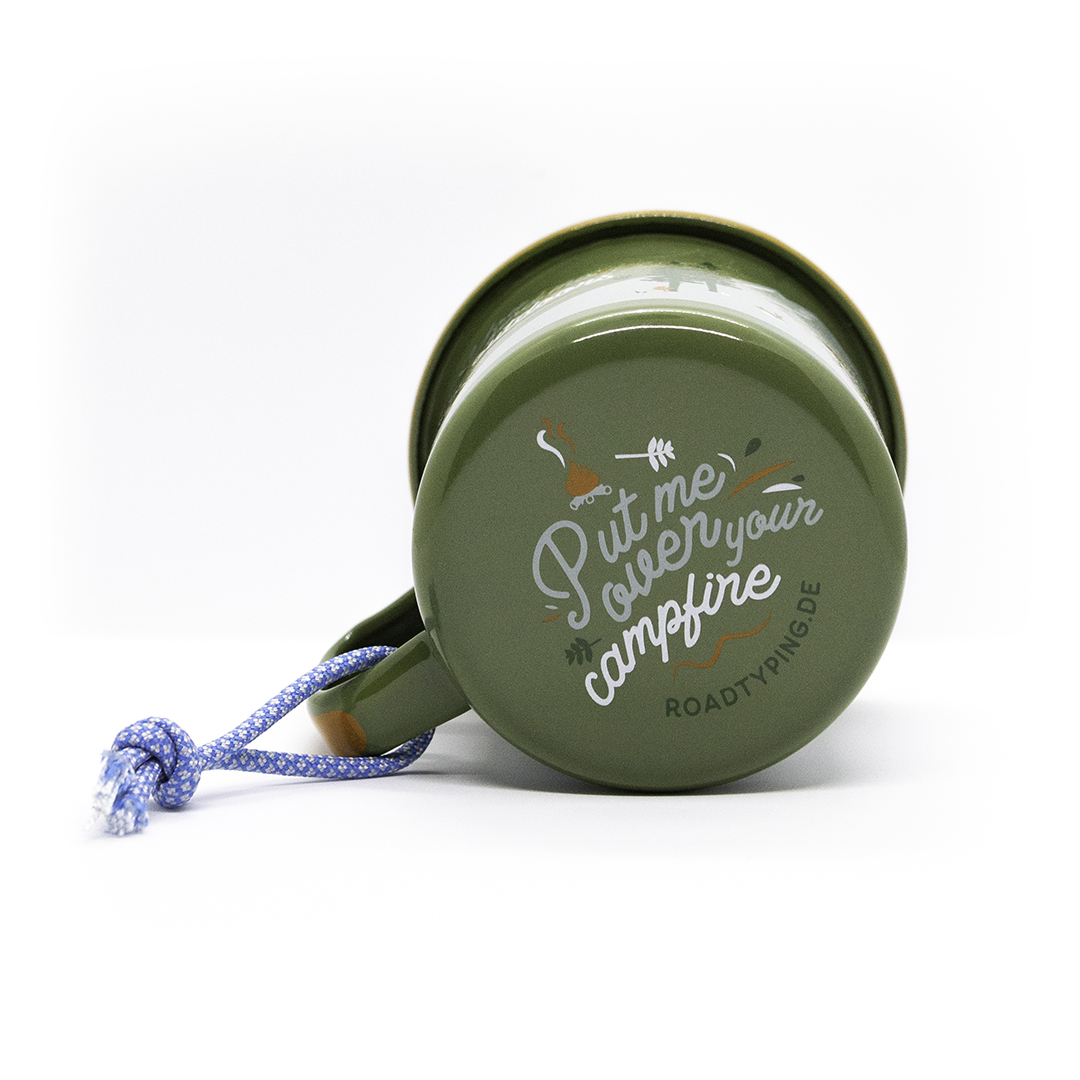 grüne Emaille Tasse mit braunem Rand und dem Aufdruck 'Put me over your campfire' auf der Unterseite